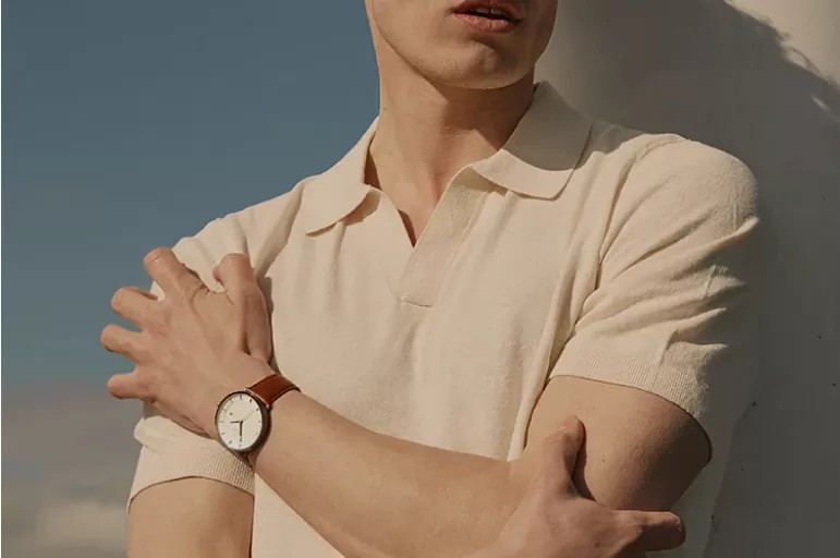 Pergelangan tangan pria dengan jam tangan sporty-chic, menunjukkan detail dial dan tali.