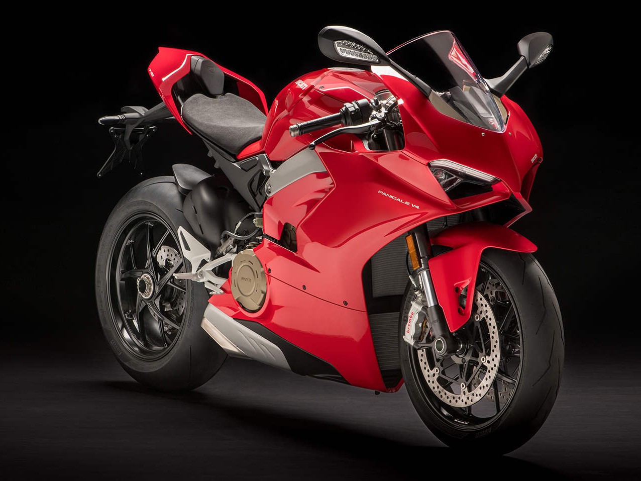 Gambar Ducati Panigale V4 di tikungan lintasan balap, miring ke tikungan dengan pengendara profesional, menekankan kecepatan dan kemampuan performanya.