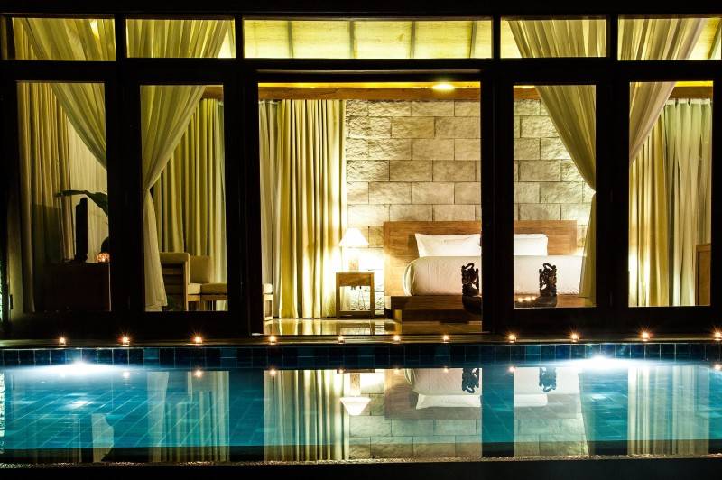 Kolam renang hotel dengan desain interior unik, mural di dinding, dan pencahayaan artistik.