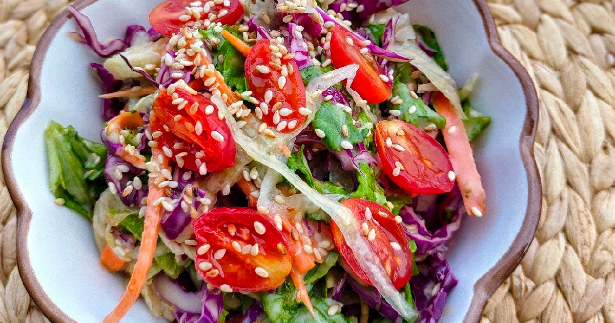 Semangkuk salad segar dengan berbagai sayuran, buah, dan kacang.