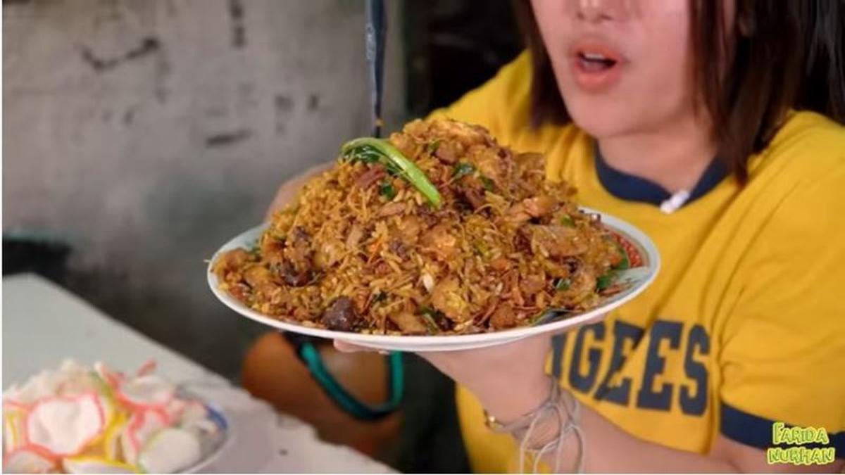 Gerobak nasi goreng di pinggir jalan dengan piring berisi nasi goreng yang baru matang.
