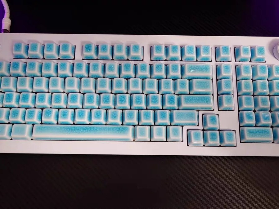Gambar keyboard mekanik dengan keycap transparan, memperlihatkan sakelarnya, dan grafik gelombang suara halus yang memancar darinya, menunjukkan profil suaranya yang unik.