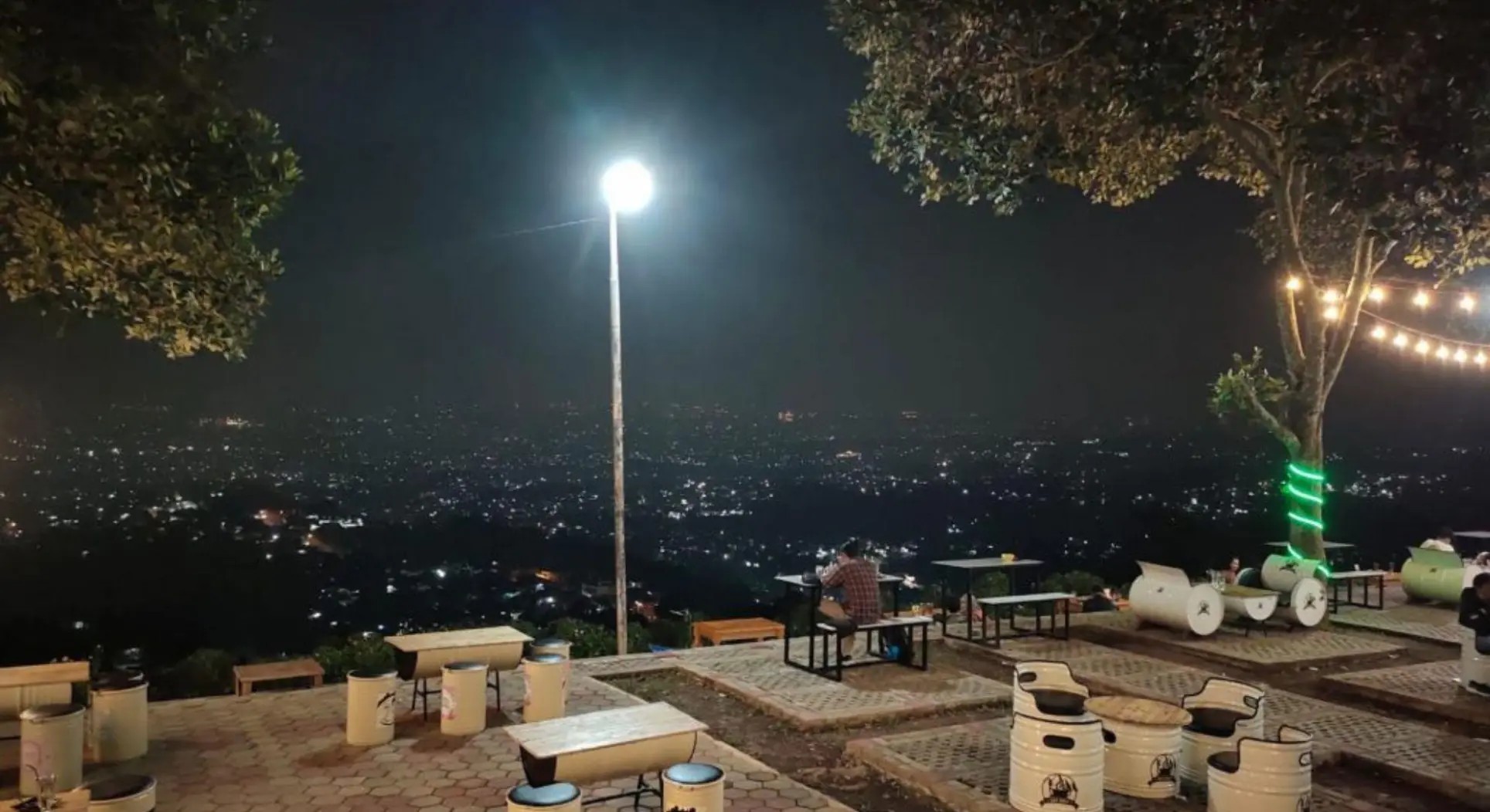 Suasana cafe rooftop di malam hari dengan city light Bandung.