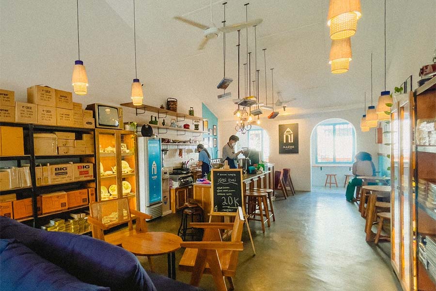 Interior cafe dengan perabotan kayu antik dan poster retro di dinding.