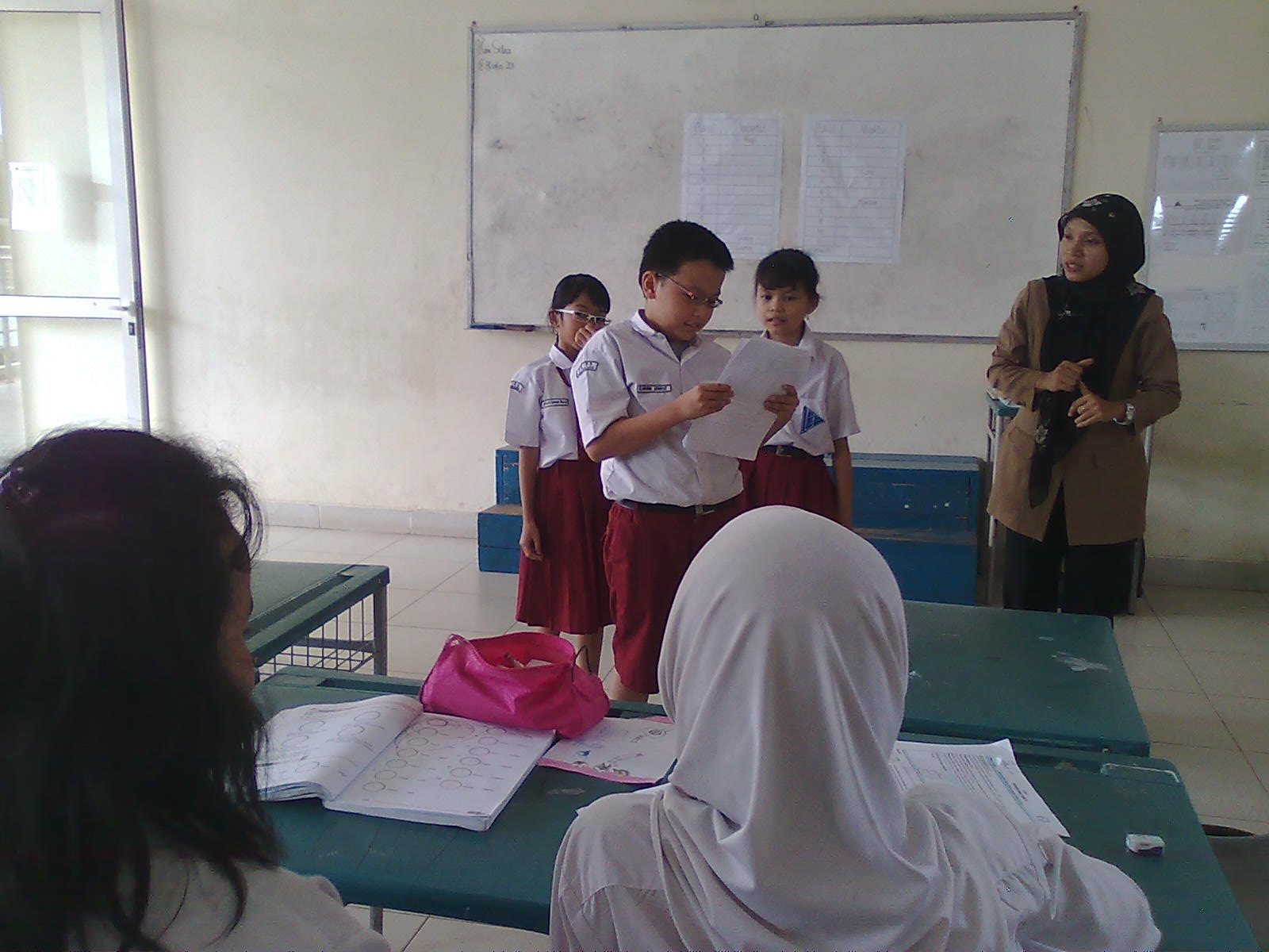 Gambar seorang siswa sedang presentasi di depan kelas dengan percaya diri, menggunakan pointer.