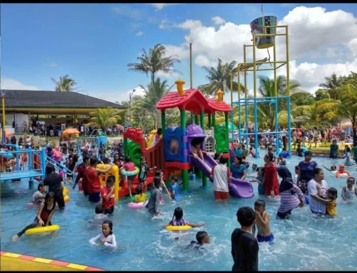 Anak-anak sedang bermain ceria di kolam renang anak dengan wahana air di taman bermain.