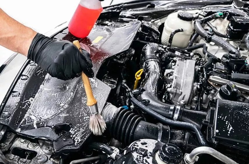 Mekanik sedang melakukan pemeriksaan rutin pada mesin mobil yang terbuka kapnya.