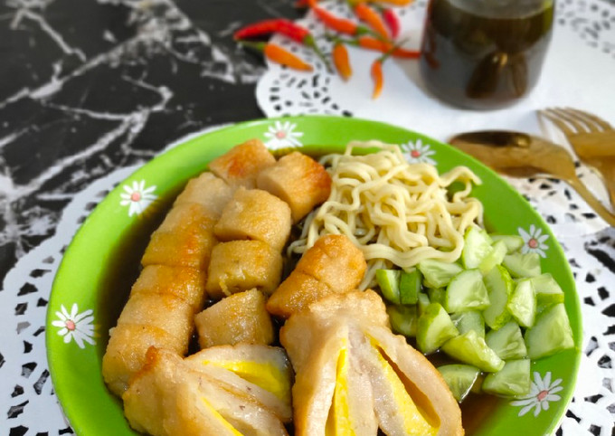 Piring berisi pempek kapal selam, lenjer, dan adaan, lengkap dengan irisan timun dan kuah cuka, suasana menggugah selera.