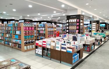 Gambar interior toko buku dengan tanda diskon dan banyak buku di rak.
