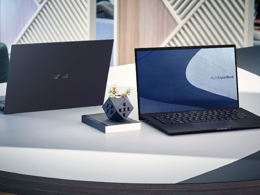 Gambar ASUS ExpertBook B9/B5 di meja konferensi atau di lounge bisnis di bandara, menonjolkan desain ramping dan portabilitasnya, dengan latar belakang pemandangan Thamrin Jakarta Pusat.