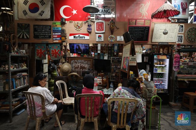 Anak muda berfoto di kafe bertema 80-an dengan dekorasi vintage dan warna cerah.