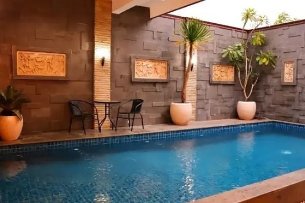 Gambar kolam renang dengan desain modern minimalis yang dikelilingi oleh kursi santai yang artistik.