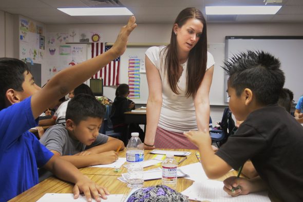 Gambar seorang guru berinteraksi dengan siswa berkebutuhan khusus di kelas, menunjukkan dukungan personal.