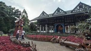 Pengunjung berpose di depan rumah hobbit dengan latar belakang suasana pedesaan Eropa di Farmhouse Lembang.