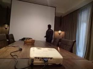 Laptop dan proyektor sedang digunakan untuk presentasi di sebuah ruangan.