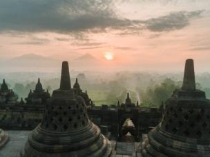 Gambar Candi Borobudur saat matahari terbit dengan pegunungan berkabut.