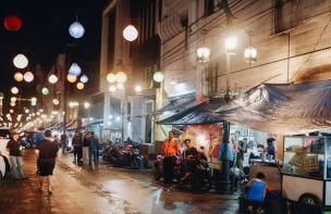 Suasana ramai di pasar kuliner malam dengan berbagai gerobak makanan yang menyala terang.