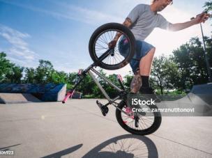 Gambar sepeda BMX GT Performer di udara saat melompat di taman skate, dengan pengendara beraksi, menonjolkan kemampuan freestyle-nya, dengan latar belakang samar Jakarta Timur.