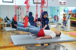 Pasien sedang melakukan latihan di pusat fisioterapi dengan bantuan fisioterapis.