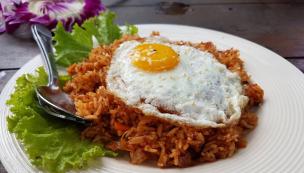 Sepiring nasi goreng dengan telur mata sapi dan kerupuk.