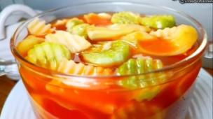 Semangkuk asinan buah dengan potongan buah segar dan kuah asam pedas.