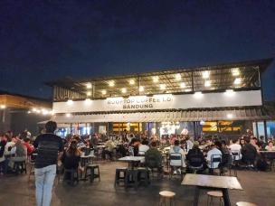 Panggung live band di rooftop cafe dengan lampu kota Bandung di latar belakang.
