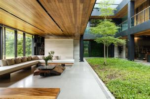 Gambar rumah modern di lingkungan hijau yang rimbun dengan banyak pepohonan.