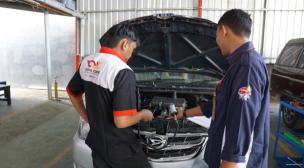 Mekanik profesional sedang melakukan pemeriksaan menyeluruh pada mesin mobil di sebuah bengkel modern.