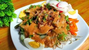 Sepiring gado-gado dengan bumbu kacang melimpah, sayuran, dan kerupuk.