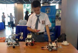 Gambar siswa-siswi sedang praktik merakit robot atau komponen elektronik di laboratorium teknik.
