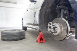 Mekanik sedang memasang coilover suspensi pada mobil sporty di bengkel.