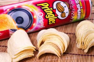 Gambar tumpukan keripik kentang berbentuk melengkung di dalam kaleng Pringles yang terbuka.