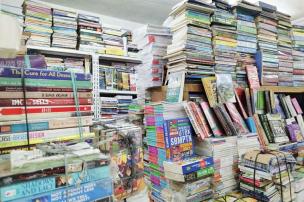Gambar interior toko buku diskon dengan banyak buku dan tanda penjualan.