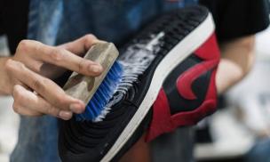 Sepatu sneakers sedang dibersihkan dengan kuas dan cairan khusus di Shoes and Care.