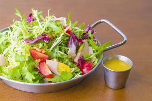 Semangkuk salad segar dengan berbagai sayuran dan protein di meja cafe.