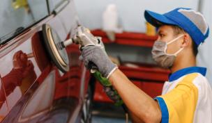 Teknisi sedang menghaluskan permukaan bodi mobil setelah proses ketok di ruang body repair.