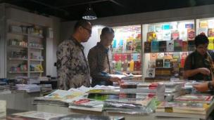 Gambar toko buku di terminal bandara dengan orang-orang melihat-lihat buku.