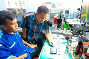 Teknisi sedang memperbaiki smartphone di meja servis di Poin Service Bandung.