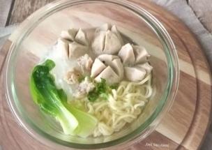 Semangkuk bakso urat dengan kuah bening, mie, dan pangsit.