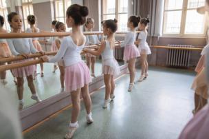 Gambar siswa-siswi sedang latihan tari balet di studio dengan cermin besar.