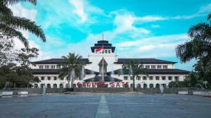Fasad Gedung Sate di siang hari dengan langit biru.