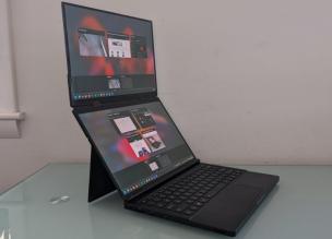 Laptop dengan dua layar terbuka, menampilkan aplikasi berbeda di layar utama dan layar sekunder.