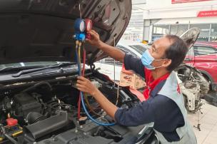 Teknisi memeriksa komponen AC mobil di bagian mesin