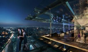 Gambar rooftop bar hotel dengan pemandangan kota di malam hari.