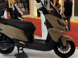 Gambar skuter listrik Gesits G1 diparkir dengan gaya di alun-alun kota atau di dekat Tunjungan Plaza, Surabaya, menonjolkan desain modern dan sifat ramah lingkungannya.