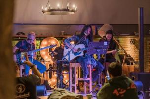 Orang-orang sedang menikmati live music di cafe yang ramai di malam hari.