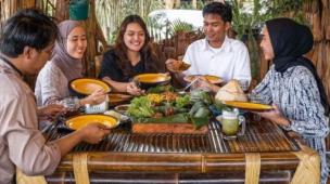 Keluarga sedang bersantap di restoran dengan pemandangan indah.