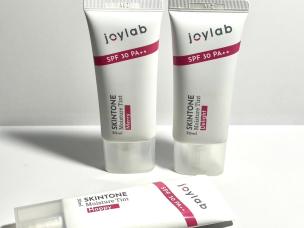 Gambar jar Joylab Skintone Moisture Gel dengan estetika cerah dan menyenangkan, mungkin dengan simbol vegan/cruelty-free, menonjolkan sifat etis dan efektifnya, dengan latar belakang samar Jakarta Sel
