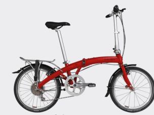 Gambar sepeda lipat Dahon Mu P8 terlipat diletakkan dengan elegan di samping meja kafe di lingkungan perkotaan, menonjolkan ukuran kompak dan nuansa premiumnya, dengan latar belakang samar Jakarta Pus