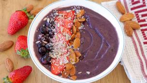 Semangkuk acai bowl dengan topping buah-buahan segar dan granola.